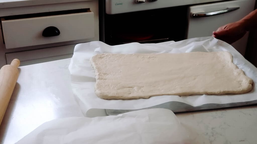 sourdough croissant dough rolled on on payment paper into a rectangle