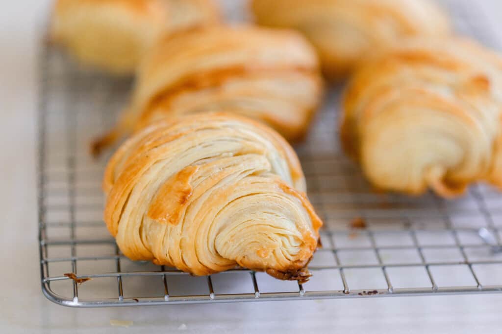 sideview of sourdough croissants on a wire wrack to cool