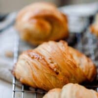 sourdough croissants on a wire rack that is laid on a white and black towel.