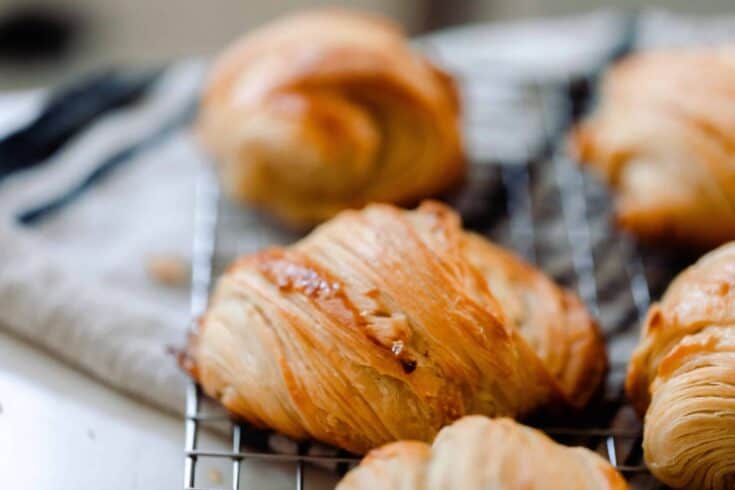 sourdough croissants on a wire rack that is laid on a white and black towel.