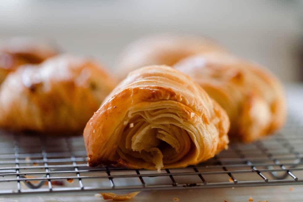 sideview of a freshly baking sourdough crescent roll revealing all the thin flakey layers