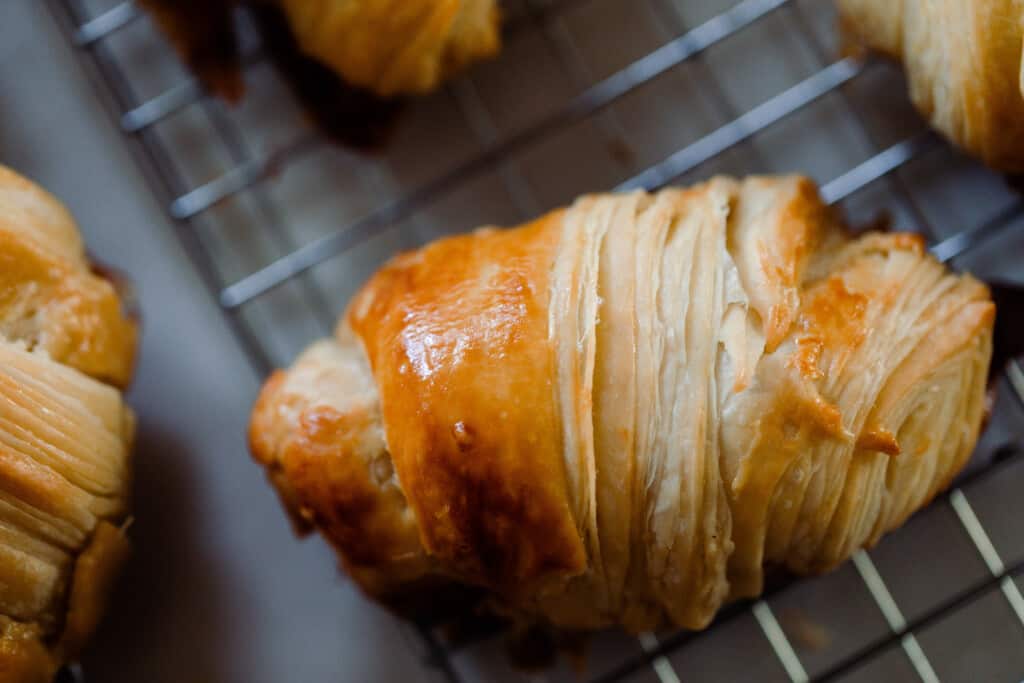 close up overhead photo of a sourdough croissant roll on a wire rack
