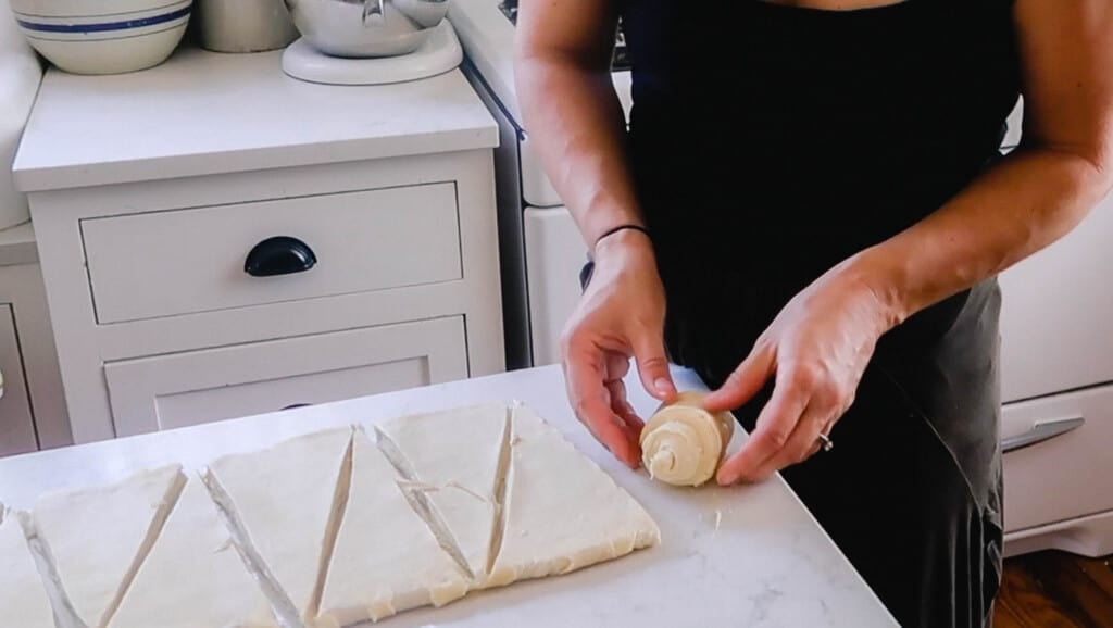 woman wearing a black shirt shaping a sourdough croissants on a white countertop