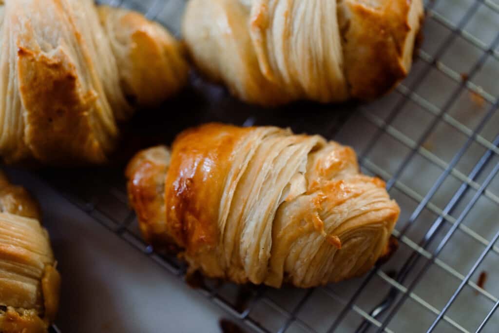 three sourdough crescent rolls on a wire rack