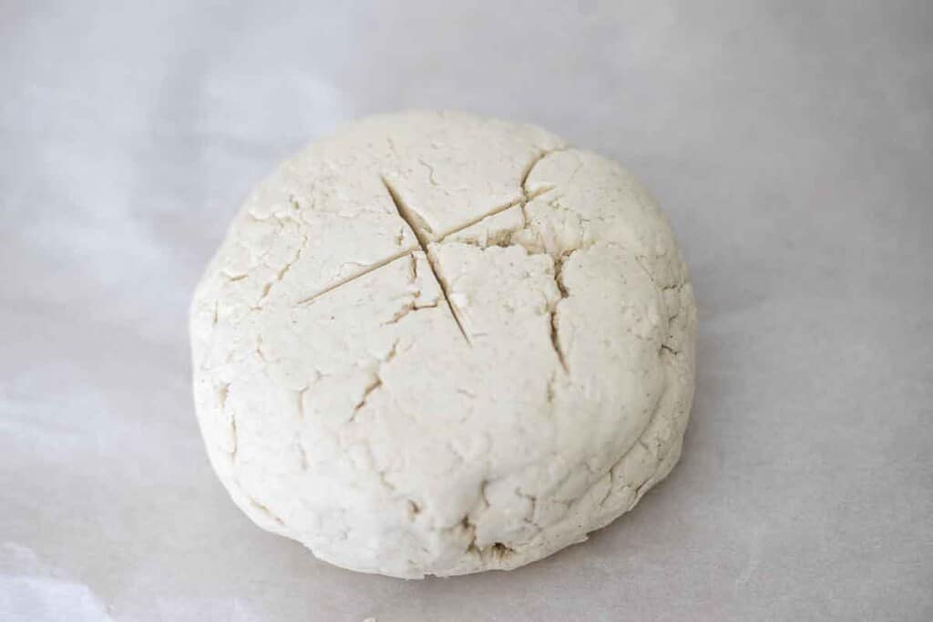 dough ball on parchment paper with an x in the middle