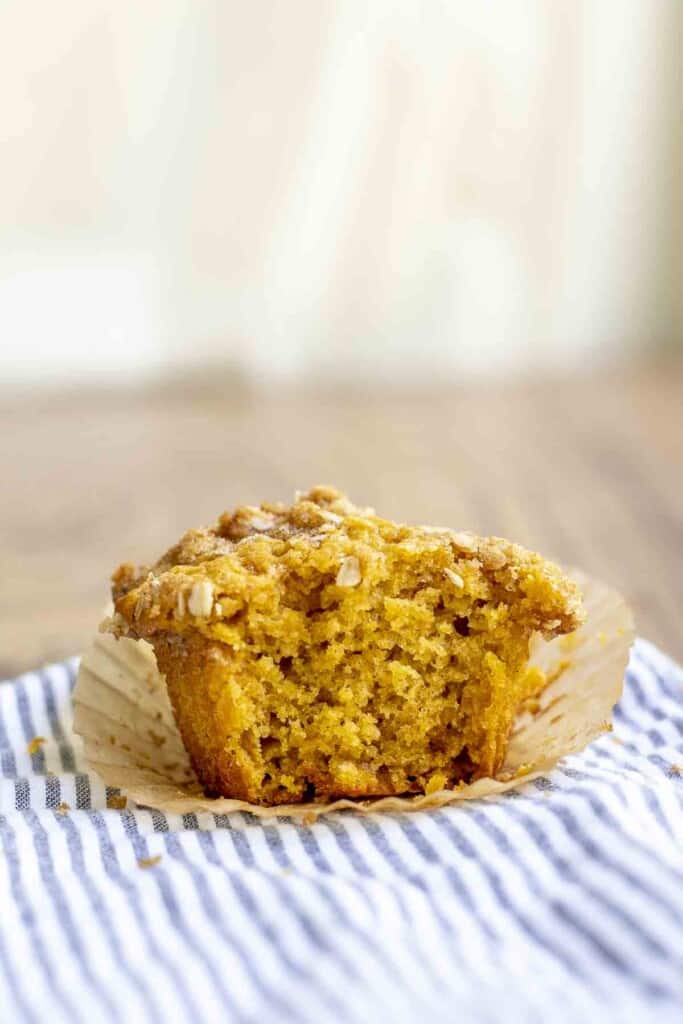 sourdough pumpkin muffin with a bite taken out on top of a white and blue striped towel