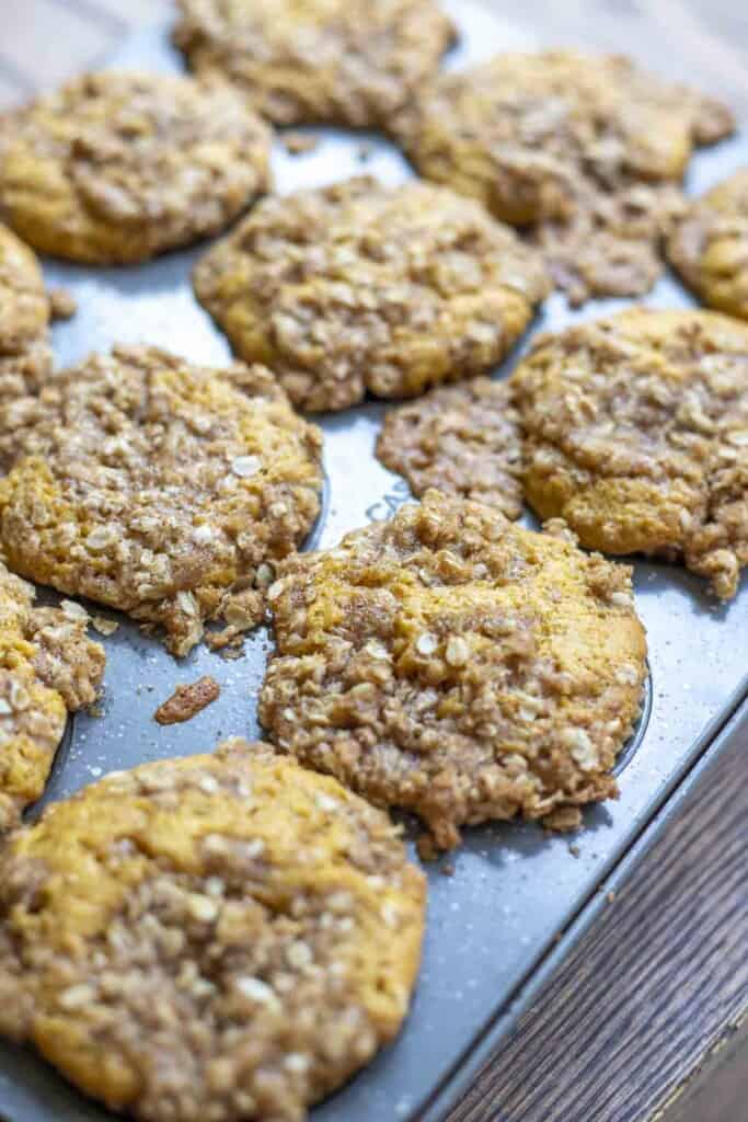 sourdough pumpkin muffins with a oat crumb topping out of the oven cooling in the muffin pan