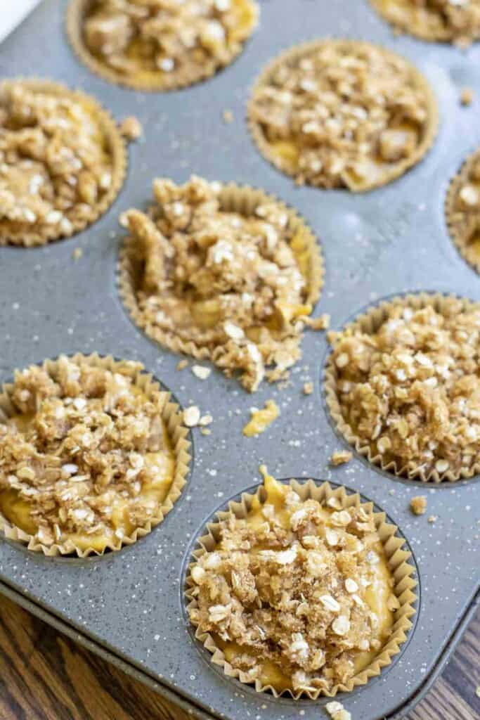 crumble oat topping on muffin batter in a muffin pan