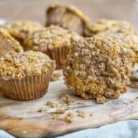 sourdough pumpkin muffins with a crumb topping spread in a wood cutting board on a green towel