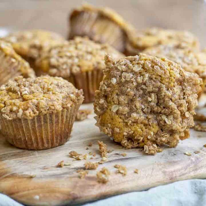 sourdough pumpkin muffins with a crumb topping spread in a wood cutting board on a green towel