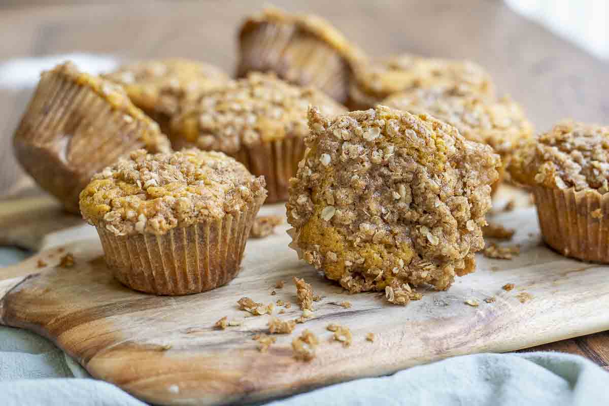 sourdough pumpkin muffins with a crumb topping spread in a wood cutting board on a green towel