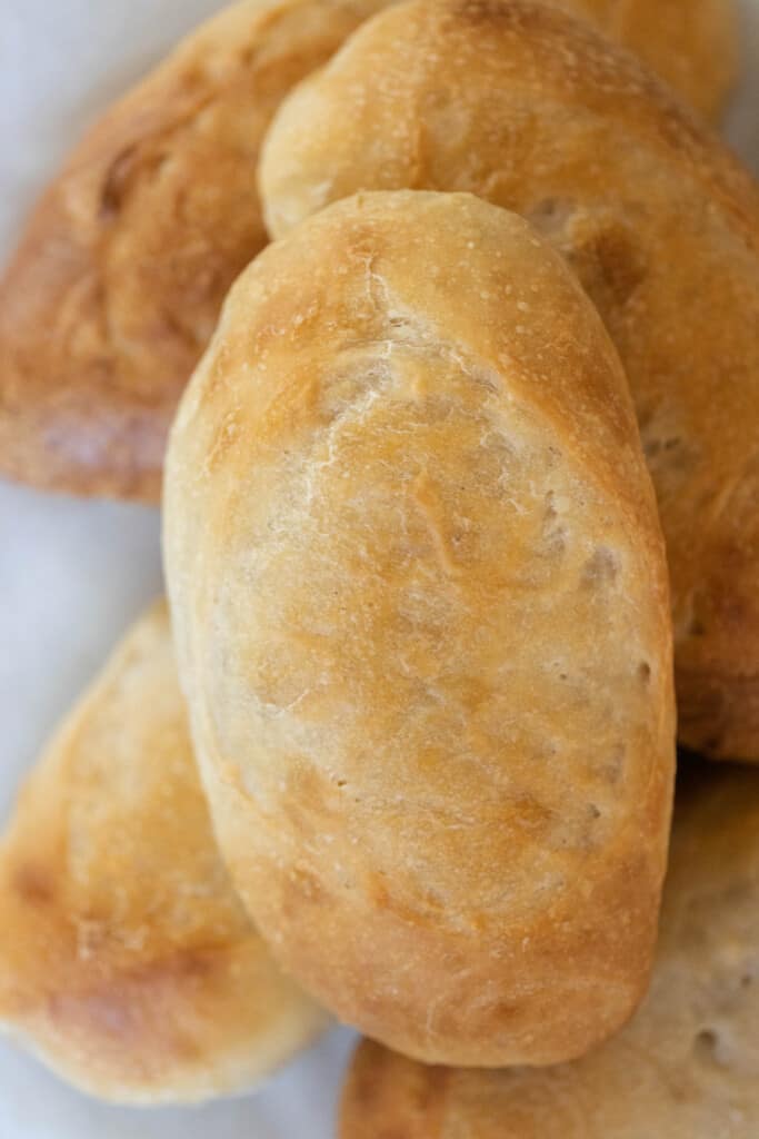 overhead photo of sourdough sandwich rolls stacked on a white countertop