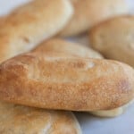 six sourdough sandwich rolls on a white quartz countertop