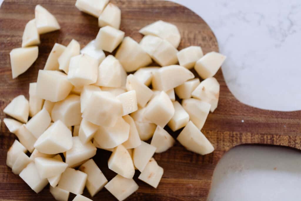 potatoes peeled and diced on a wood cutting board