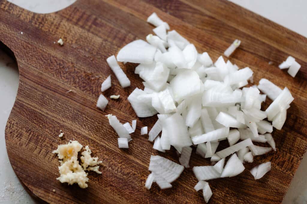 onions and garlic diced on a wood cutting board