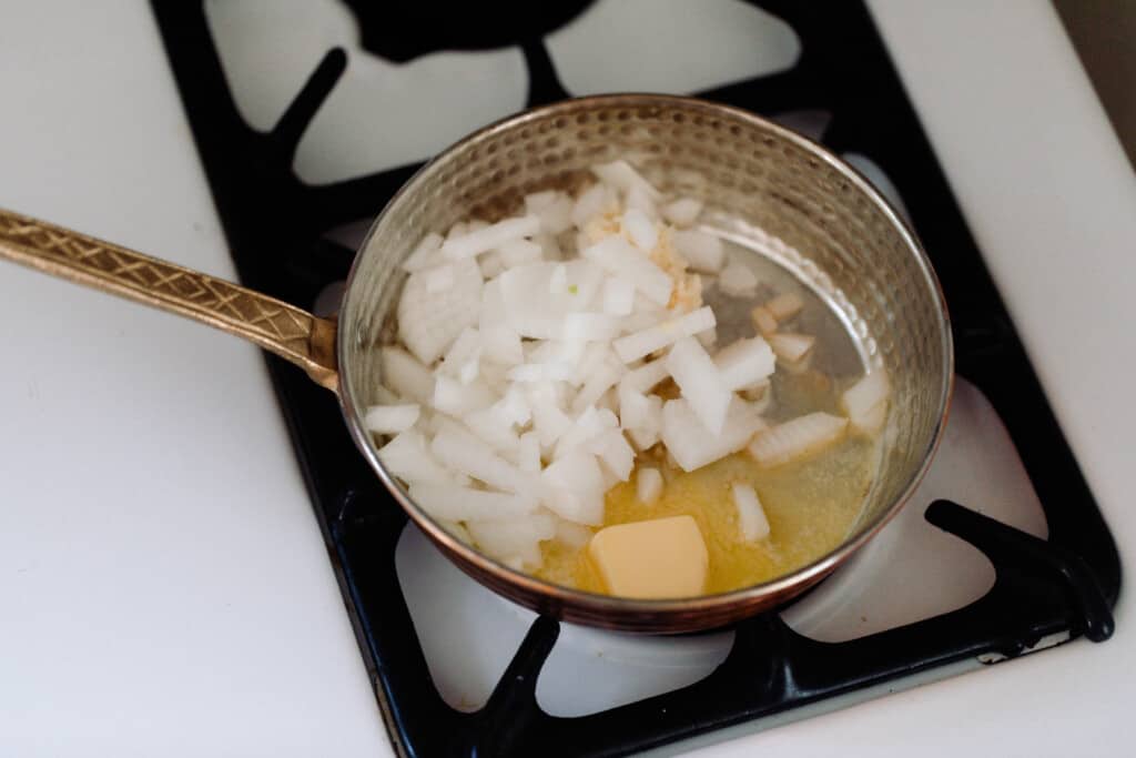 butter and onions sautéing with butter in a copper skillet