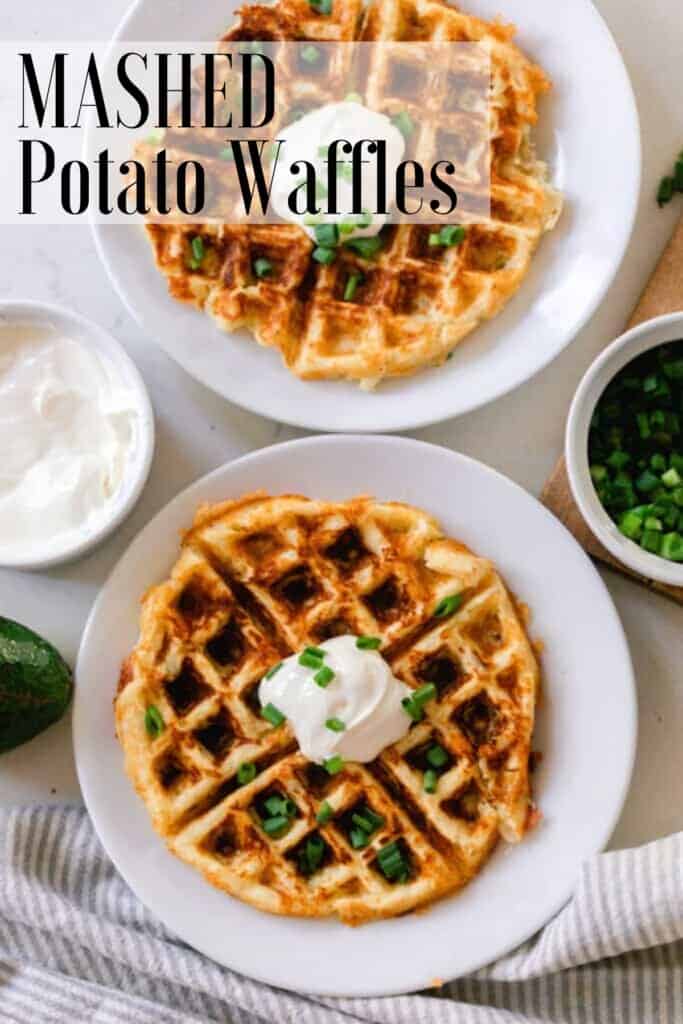 two potato waffles on a white plate topped with sour cream and chives. The plates rest on a white countertop with little jars of chives and sour cream