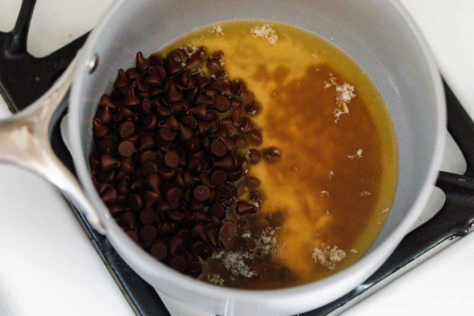 Melted butter with chocolate chips and vanilla in a white pot.