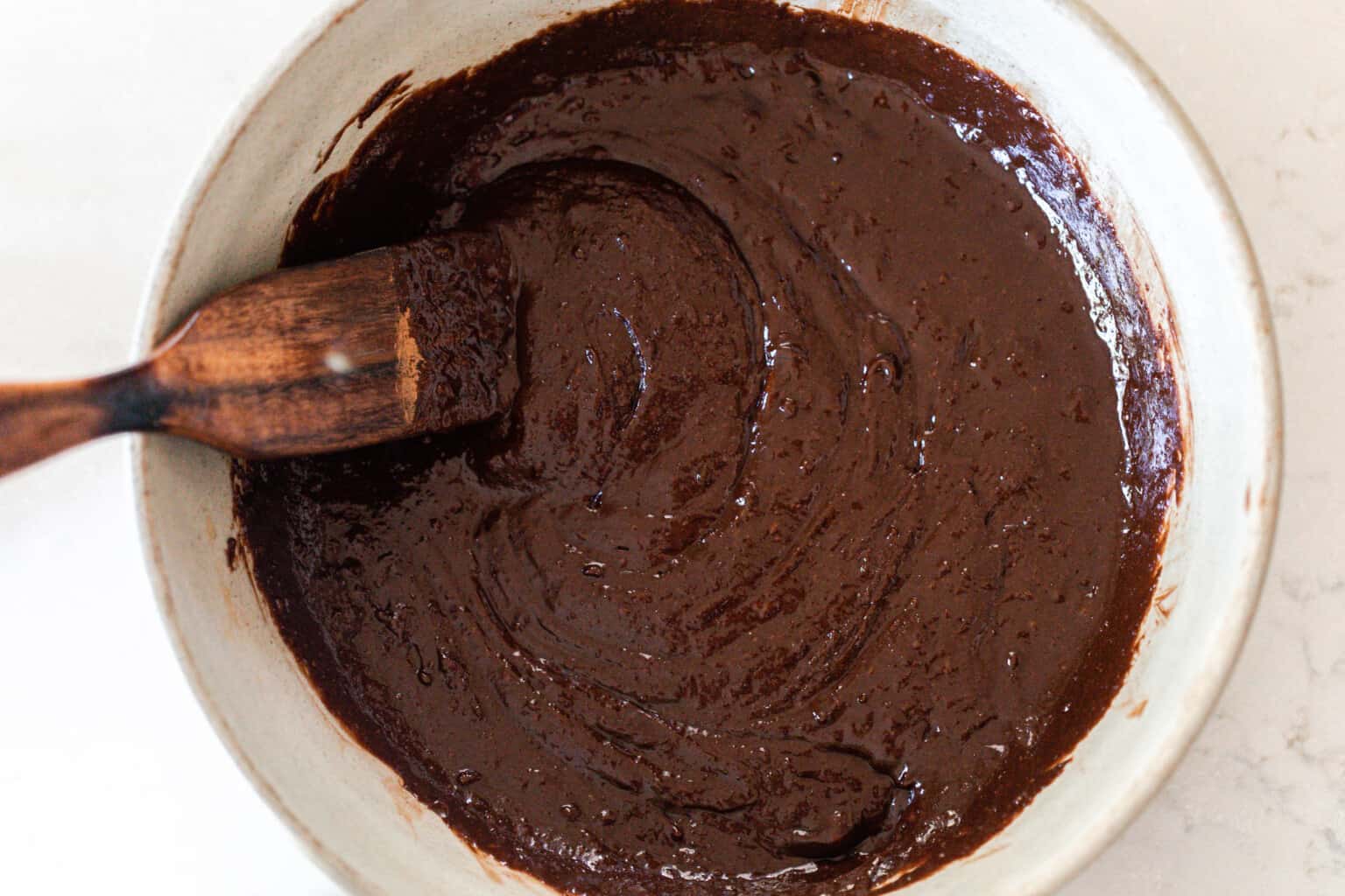 Sourdough brownie batter in a large bowl with a wooden spatula.