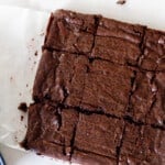 overhead photo of sourdough brownies cut into squares on parchment paper