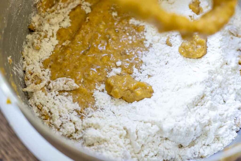 flour being added into wet ingredients in a stand mixer bowl