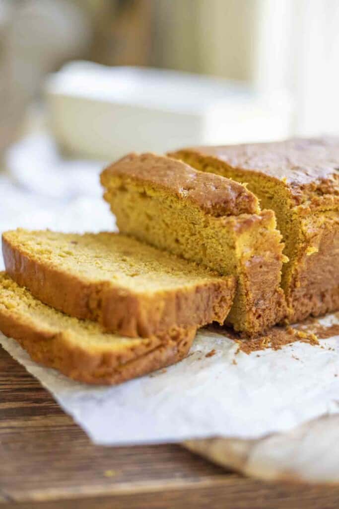 sourdough pumpkin bread sliced on top of a parchment paper on a wood cutting board