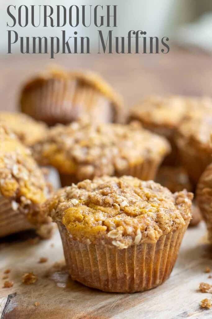 sourdough pumpkin muffin with oat crumb topping spread out on a wood cutting board on a wooden table