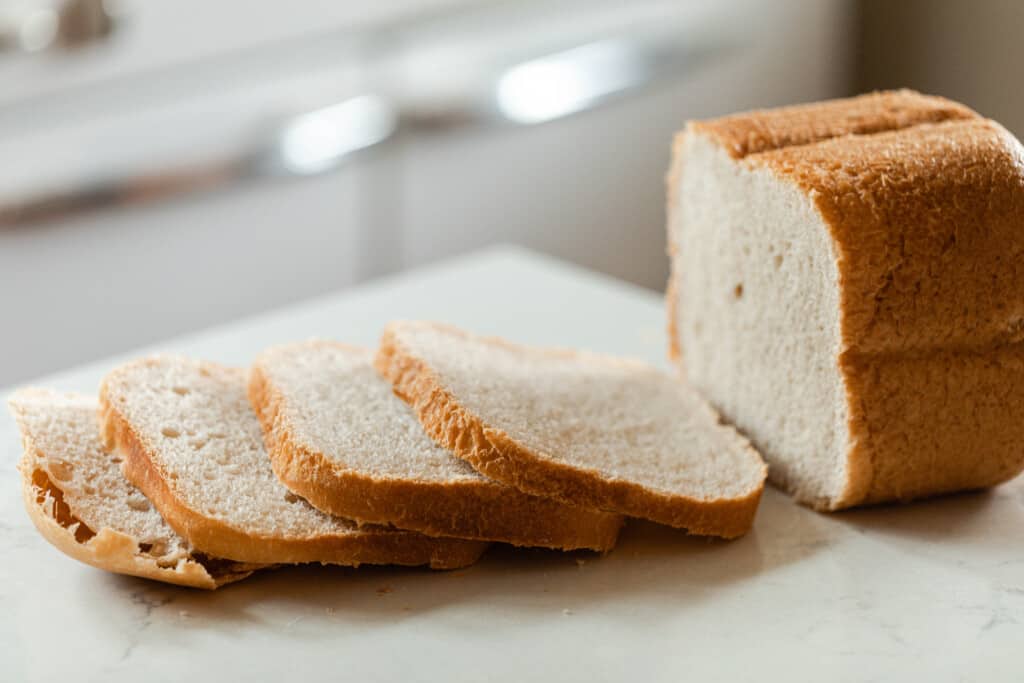 loaf of sourdough bread from a bread machine cut on a white quartz countertop