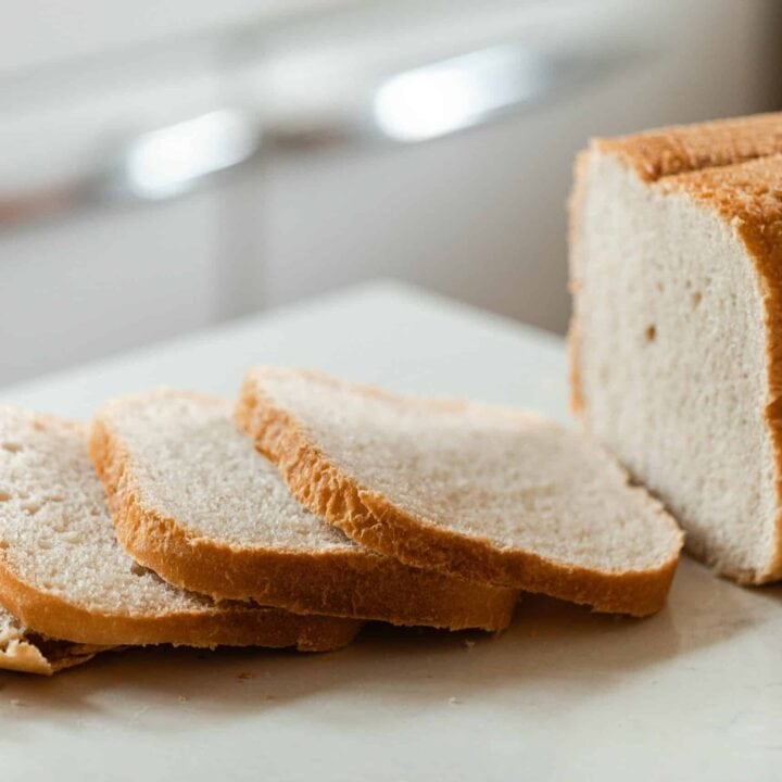 loaf of sourdough bread from a bread machine cut on a white quartz countertop