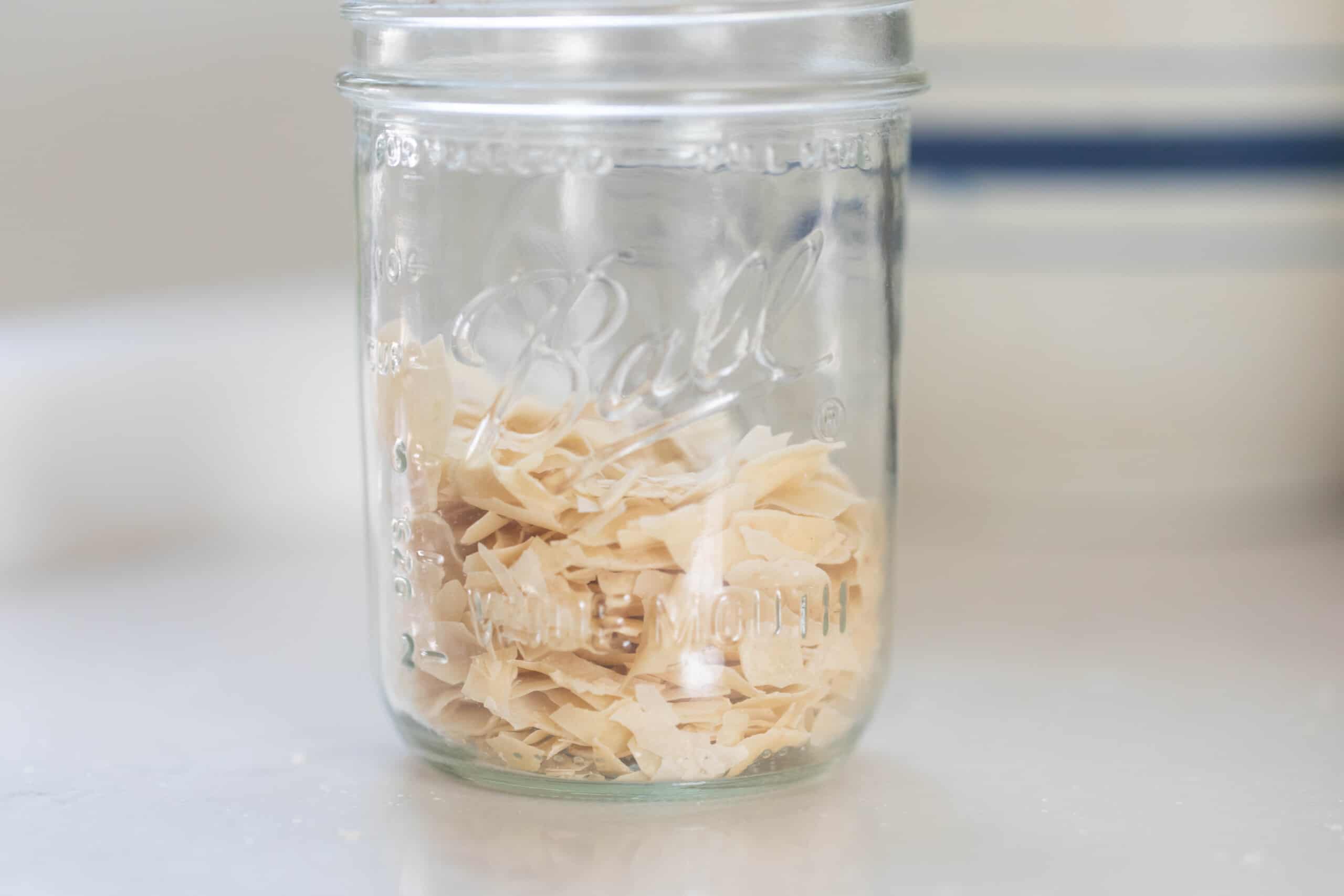 dry sourdough starter in a glass mason jar on a white countertop