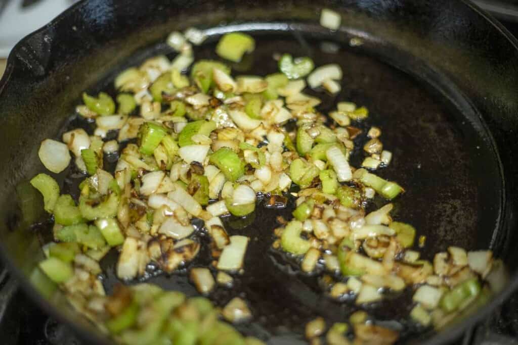 Celery and onions sautéing in a cast iron skillet.
