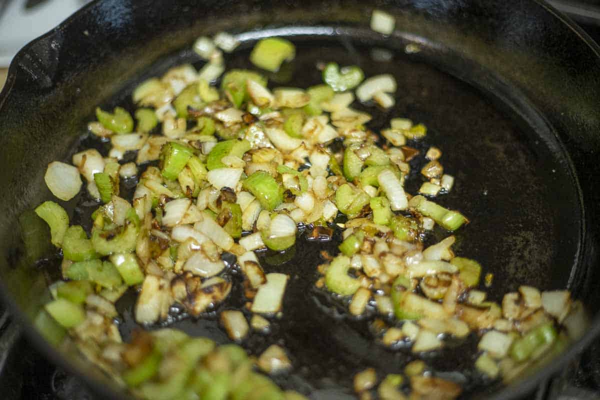 Celery and onions sautéing in a cast iron skillet.