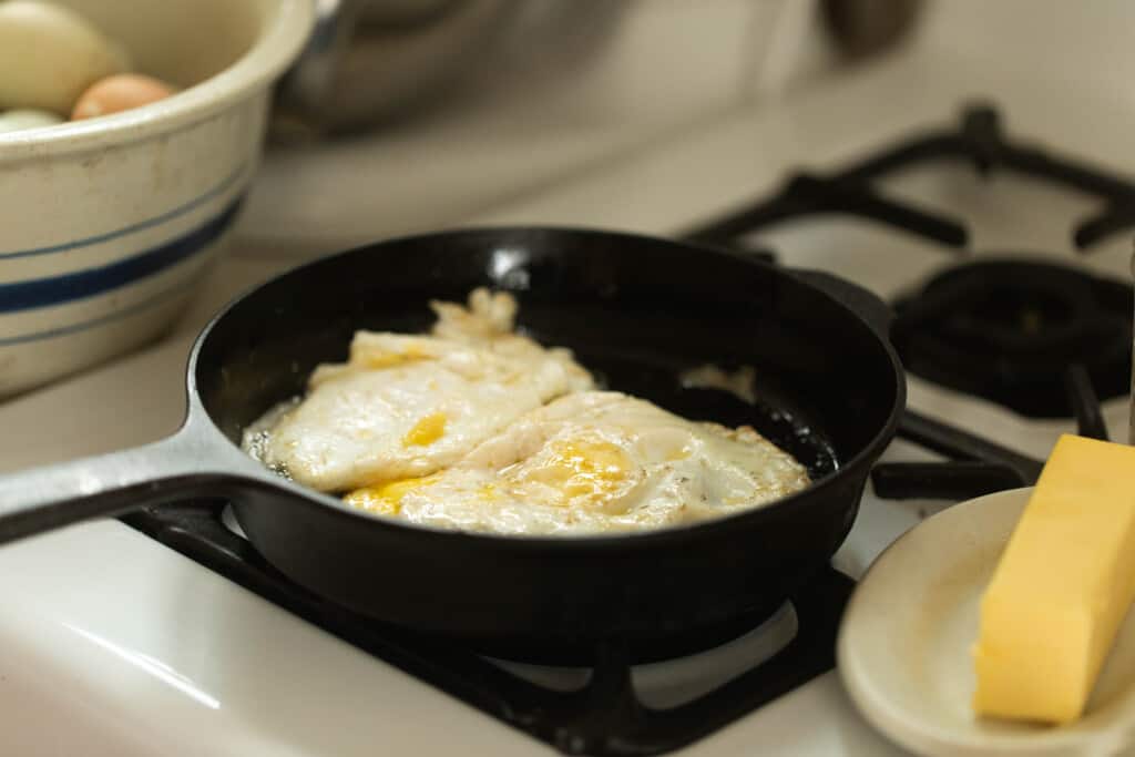 over hard egg cooking on a small cast iron skillet on a white stove