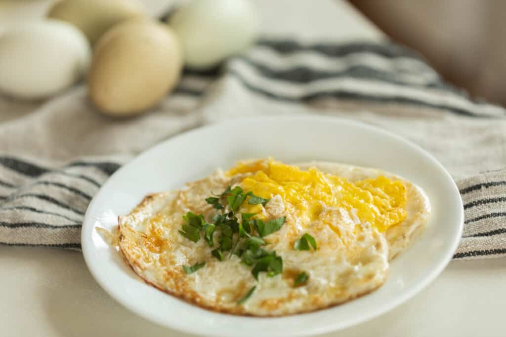 plate of over hard fried eggs on a white and black stripped towel with eggs in the background