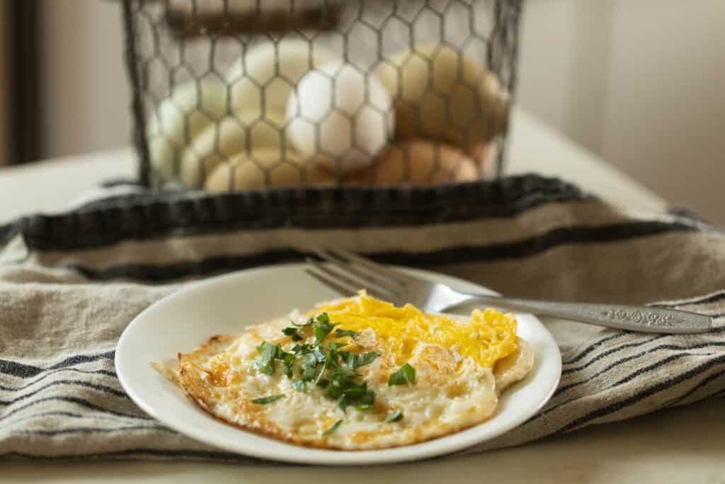 white plate with over hard eggs on a white and black stripped towel with a basket of eggs in the background