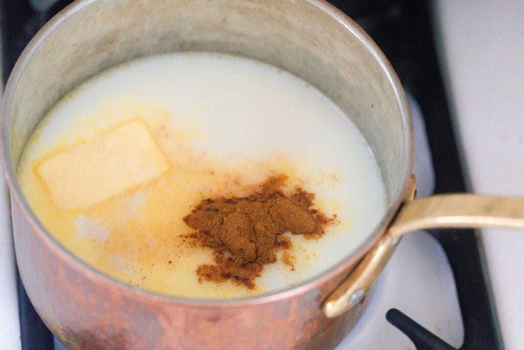 milk, butter, sugar, and cinnamon in a copper pot on a stove