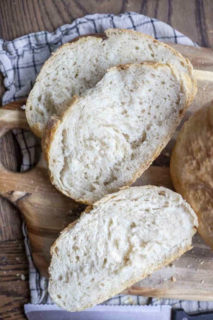 slices of sourdough discard bread on a wood cutting board on top of a white and black checked towel