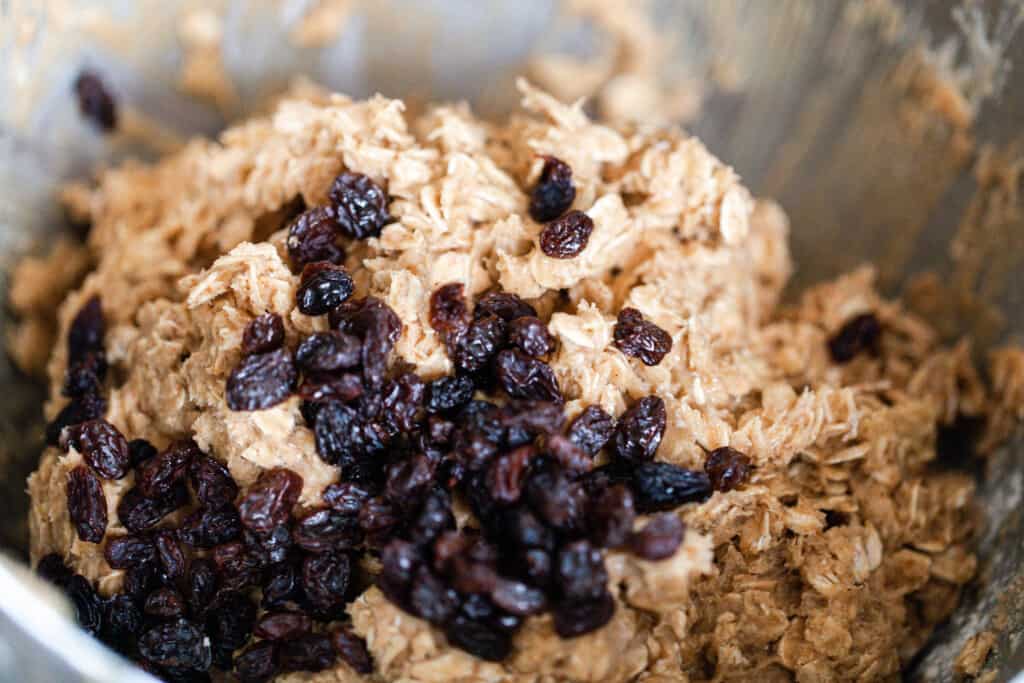 raisins added to sourdough oatmeal cookie dough in a stand mixer bowl