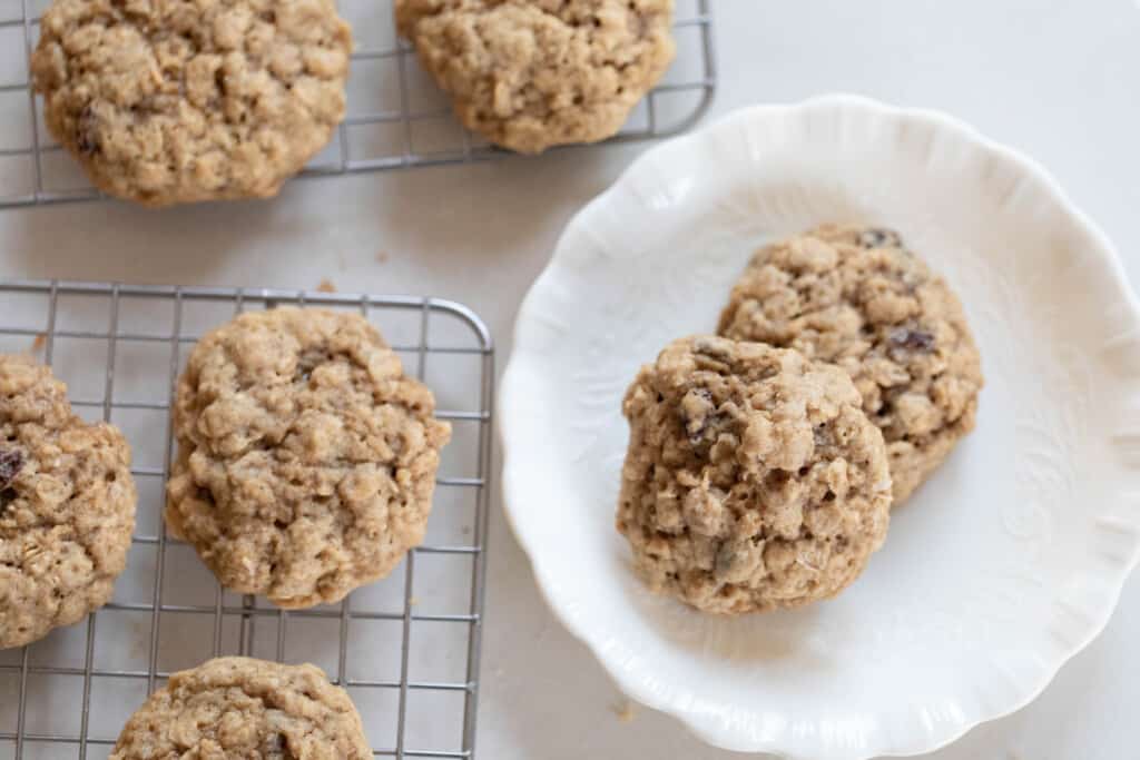 overhead photo of sourdough oatmeal discard cookie on a white plate with wire racks of more cookies to the left