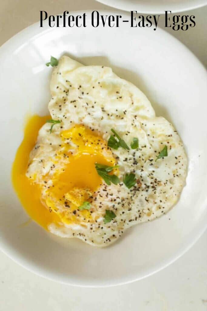 overhead photo of over easy eggs topped with fresh herbs on a white plate