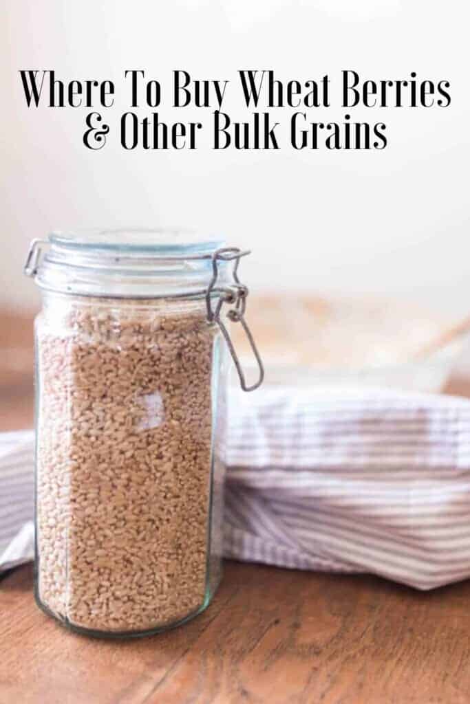 swing top jar full of wheat berries on a wood table with a blue and white towel behind it.