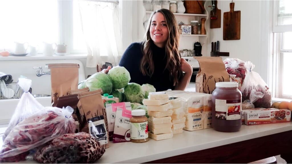 a woman standing behind an kitchen island with grocers spread out over the counter