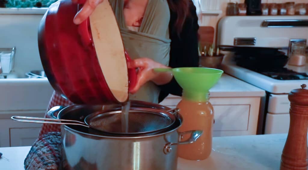 straining lard through a fine mesh strainer into a pot