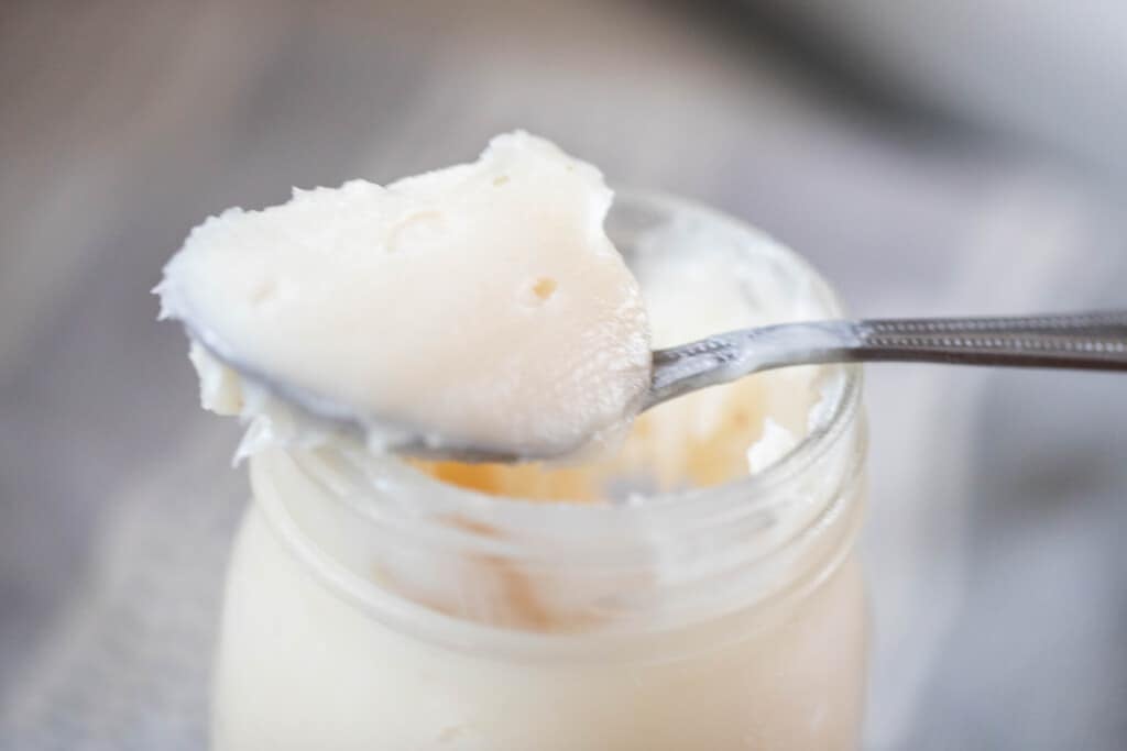 spoonful of lard resting on a mason jar of rendered lard