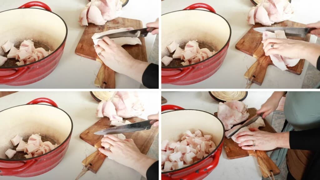 chopping pork fat into small pieces on a wood cutting board and placing it in a red dutch oven