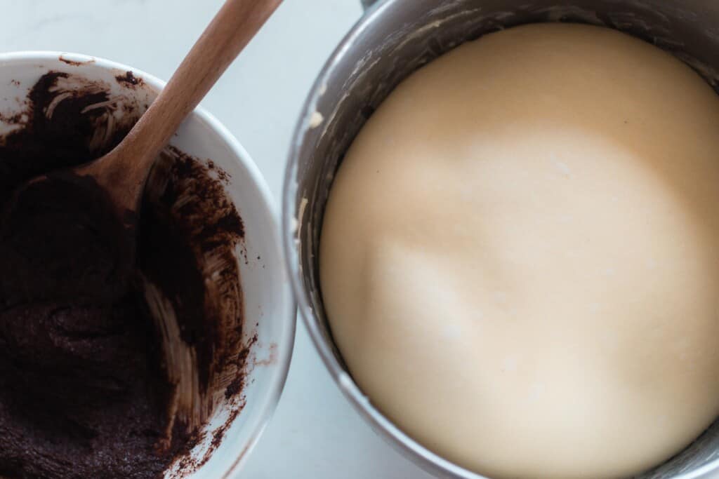 sourdough brioche bread dough in a metal bowl with a bowl to the left with chocolate filling