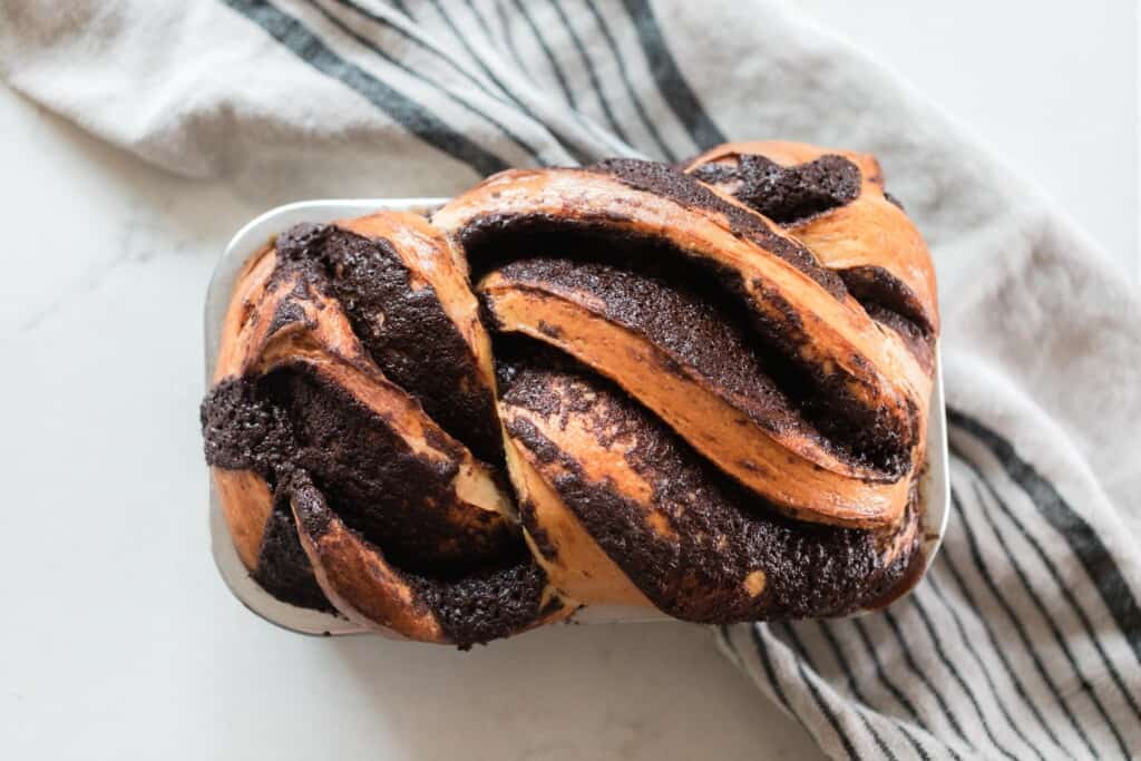 overhead photo of sourdough babka with chocolate filling on a white and black stripped towel