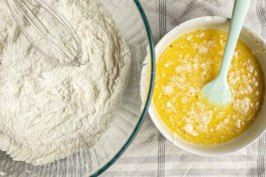 glass bowl of dry ingredients and a white bowl of melted butter, sourdough starter, and water to the right