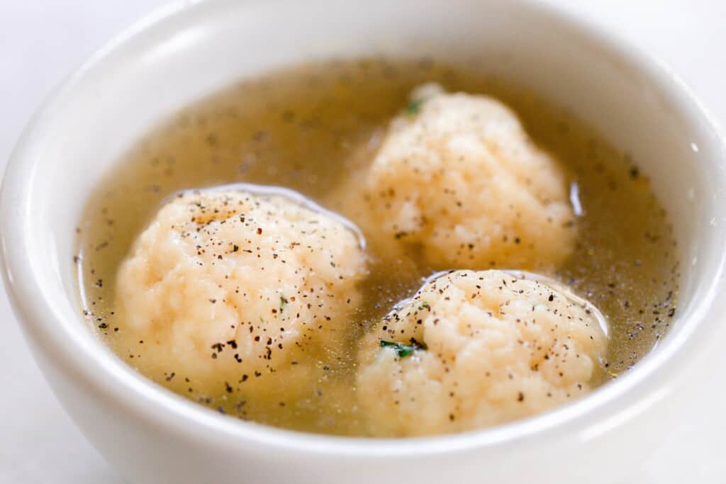 close up of sourdough dumplings and soup in a white bowl