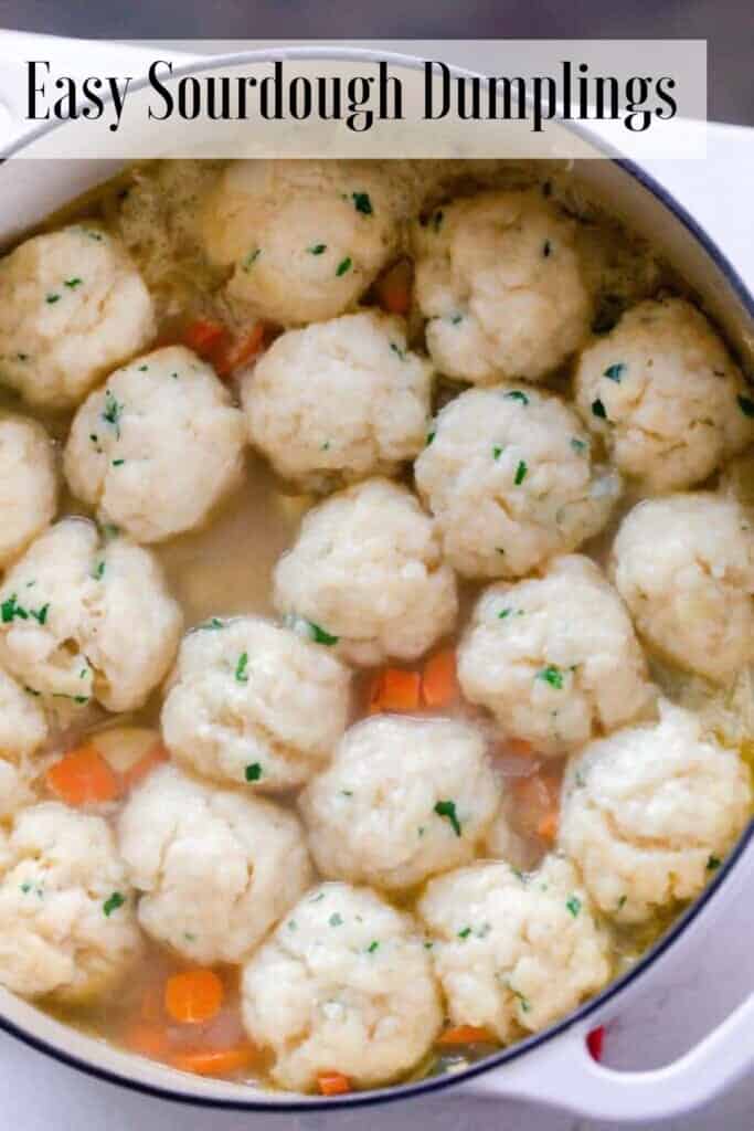sourdough dumplings simmering in chicken soup in a white dutch oven